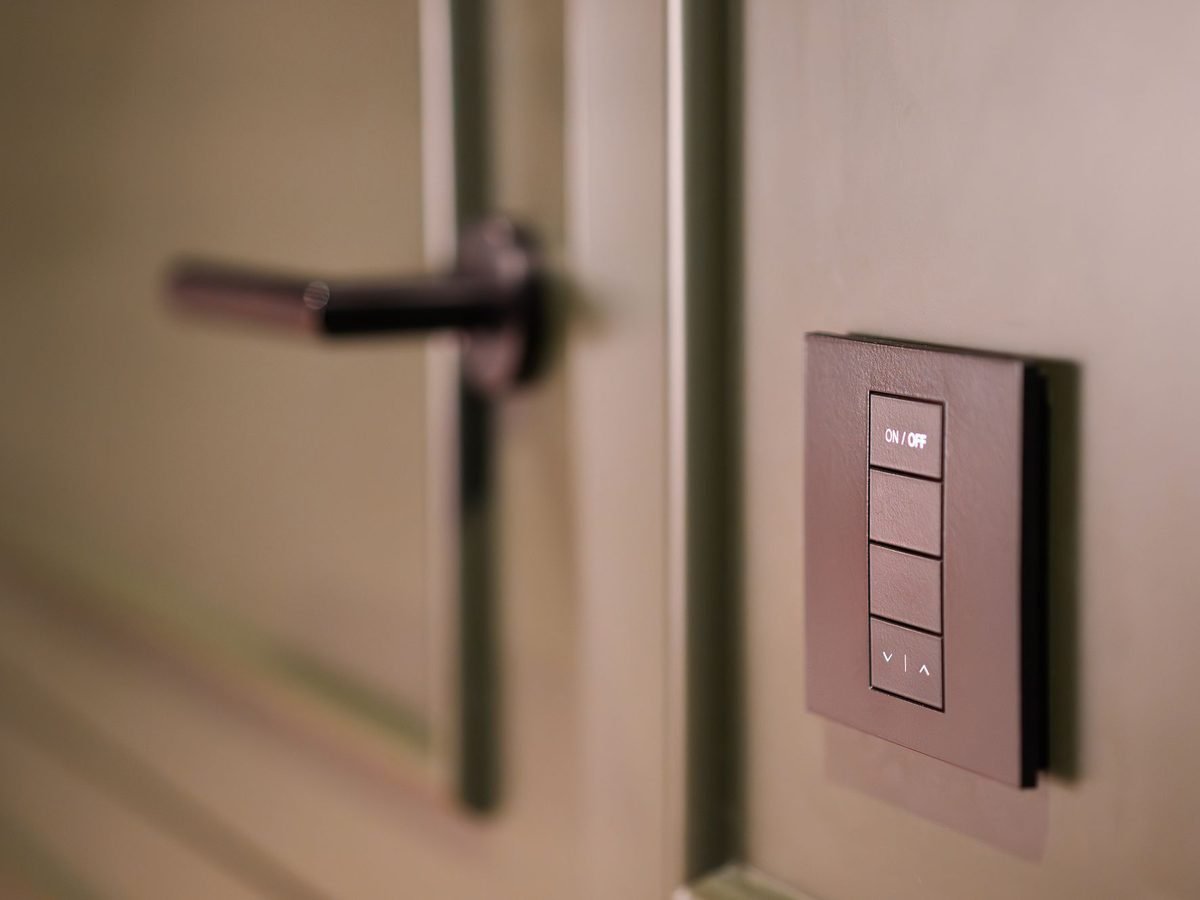 Smart light switch on a wall next to a modern door handle